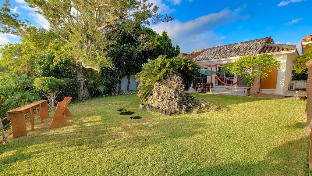 ein Haus mit einem Garten mit einem Baum in der Unterkunft Océanos - Sunset, BBQ, Beach & Kayak - オケアノス in Ishigaki-jima