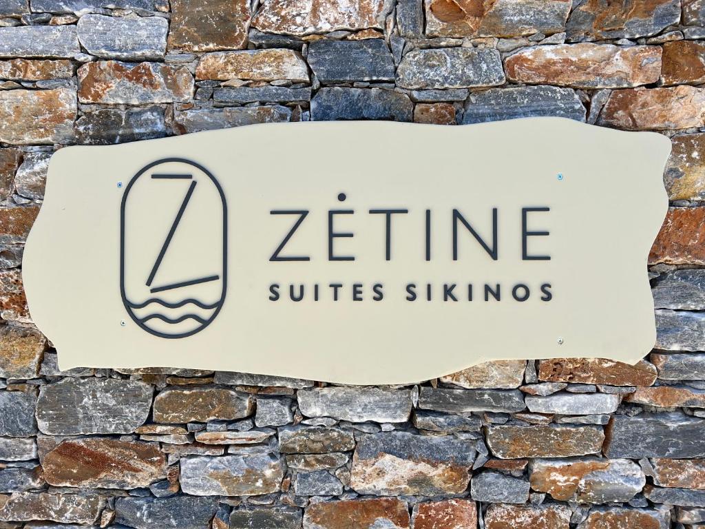 un cartel en una pared de ladrillo con las palabras "zine Suites slingers" en ZETINE SUITES SIKINOs en Síkinos