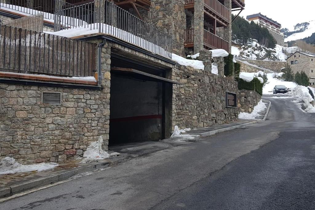 um edifício de pedra com uma garagem numa rua nevada em Apartamento en Vall d'Incles em Incles