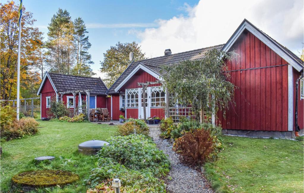 un granero rojo con un jardín delante de él en Bjrnhult,, en Tjörnarp