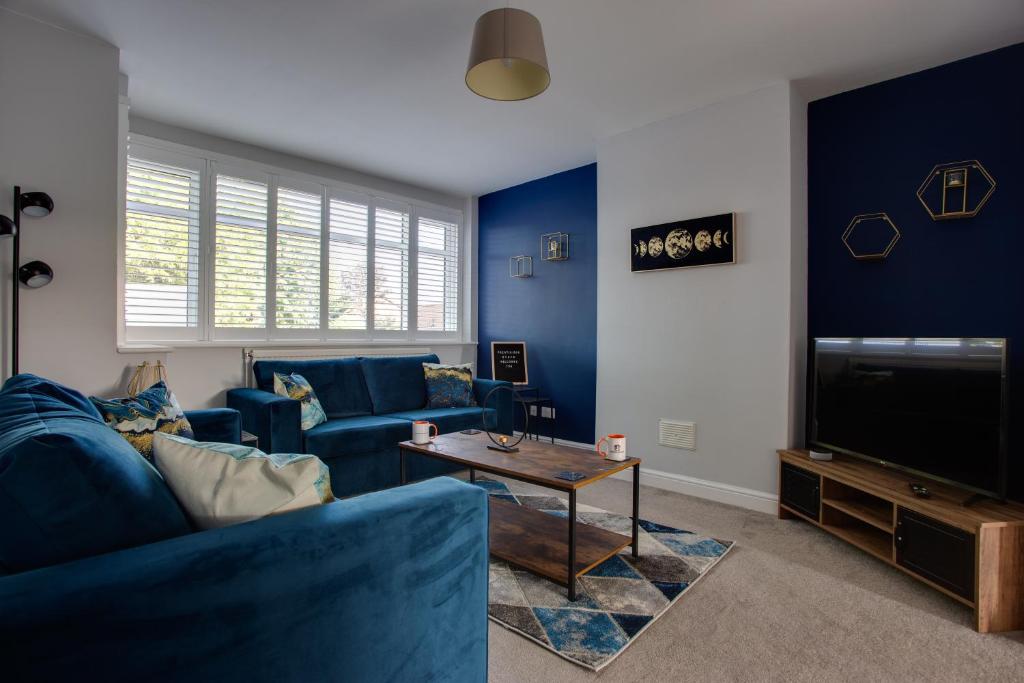 a living room with blue furniture and a tv at SAXON ROAD - A 3 Bedroom House with Garden by Prestigious Stays - Includes Wifi, Netflix & Amazon Alexa in Sunbury Common