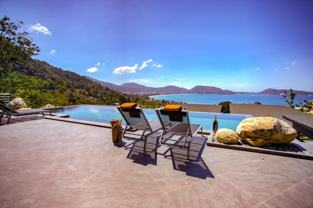 - une piscine avec des chaises et une vue sur l'océan dans l'établissement Ocean Rock Kalim, à Patong Beach