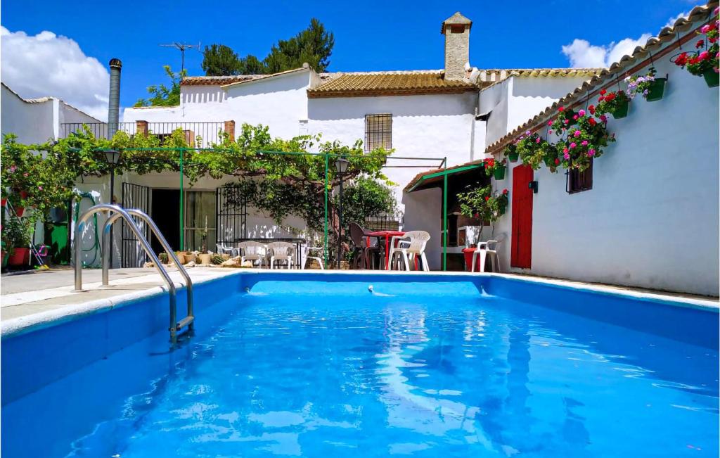a blue swimming pool in a yard with a house at Stunning Home In Campos Nubes-priego With 5 Bedrooms, Outdoor Swimming Pool And Swimming Pool in Campo-Nubes