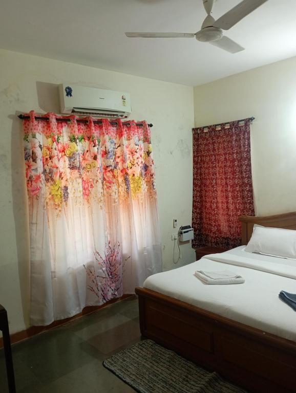 Lobos villa في كالانغيُت: غرفة نوم بسرير وستارة عليها ورد