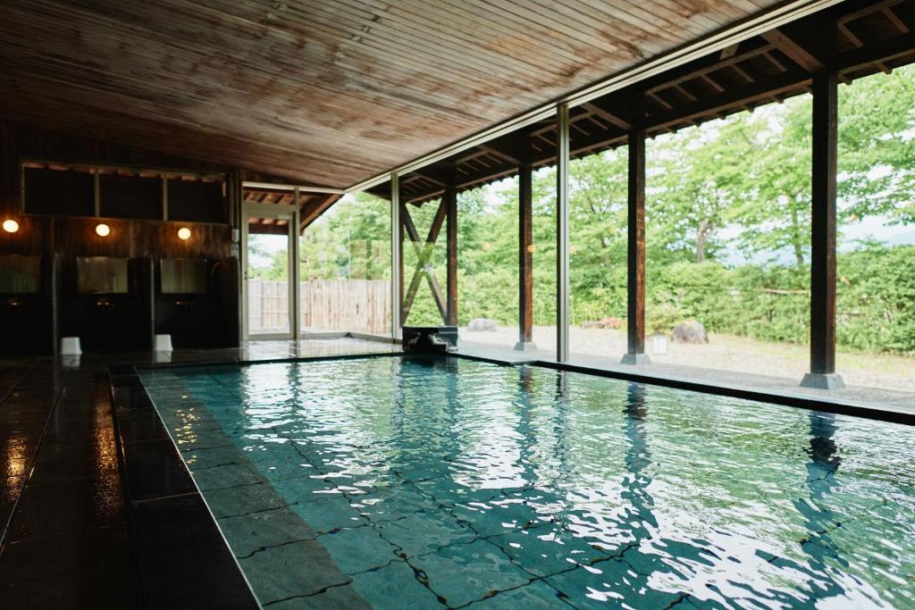une piscine dans un immeuble avec une grande fenêtre dans l'établissement Takamiya Ryokan Sagiya Sansorai, à Kaminoyama