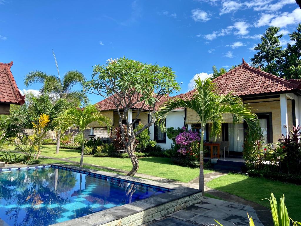 a house with a swimming pool in front of a yard at Wonder Dive Bali Tulamben Villa's in Tulamben