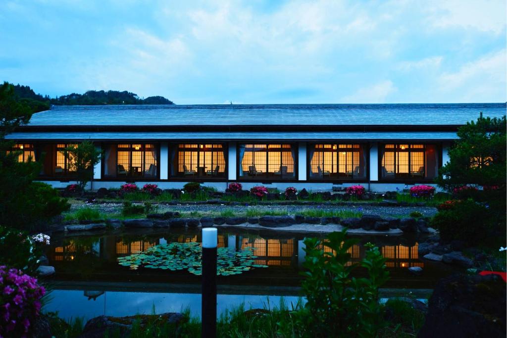 un edificio con un estanque delante de él en Takamiya Ryokan Sagiya Sansorai en Kaminoyama