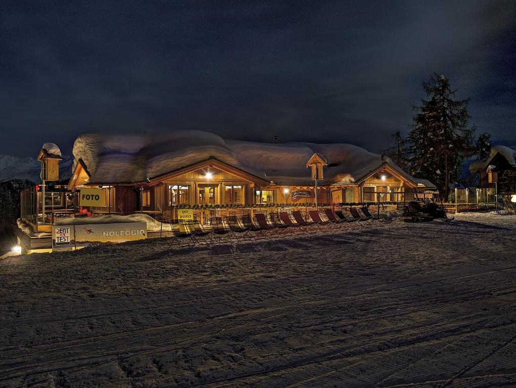 a large wooden house with snow on the roof at night at Chalet Degli Angeli in Folgarida