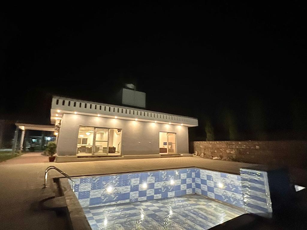 a building with a swimming pool at night at entire farm and pool for holi party 3bhk with very big hall in Gurgaon