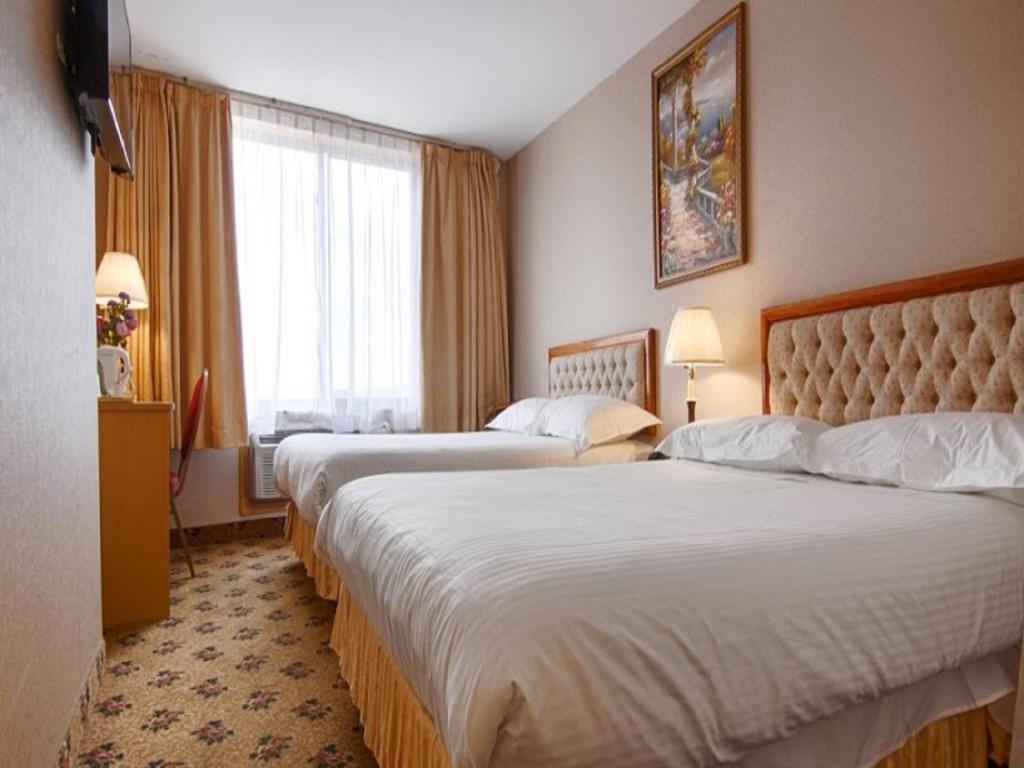 a hotel room with two beds and a window at Flushing Hotel in Queens