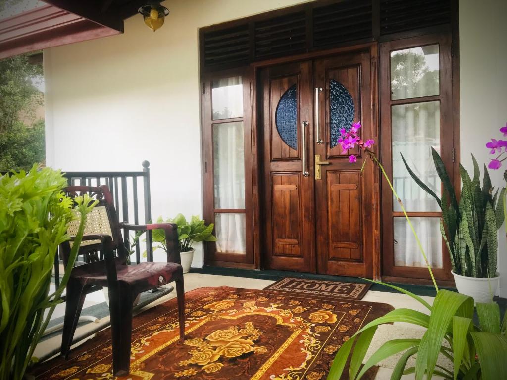 a room with a wooden door and a chair and a rug at Mirador Cottage in Bandarawela