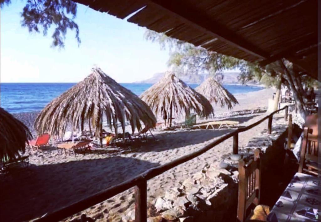 einen Strand mit Strohschirmen und dem Meer in der Unterkunft Orea Kaliva in Sfinárion