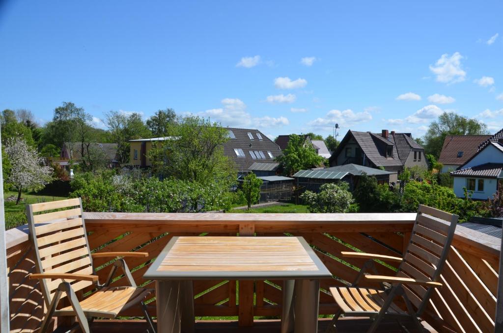 un tavolo in legno con sedie e un balcone con vista. di FEWO-Kramm Ostseebad Dierhagen a Dierhagen