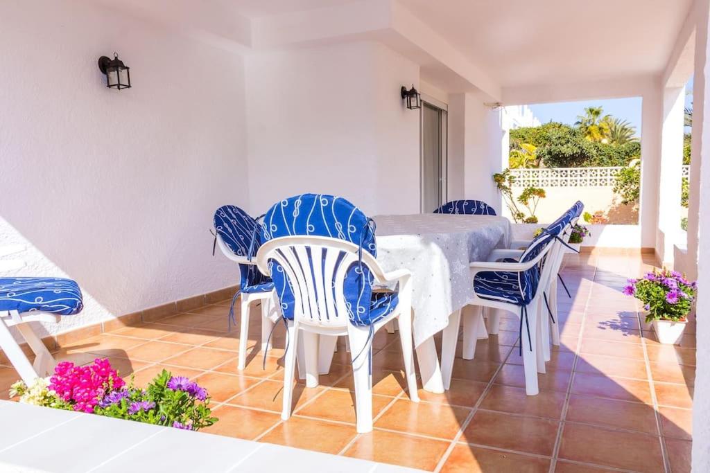 a dining room with a white table and blue chairs at Villa El Arenal in Mojácar