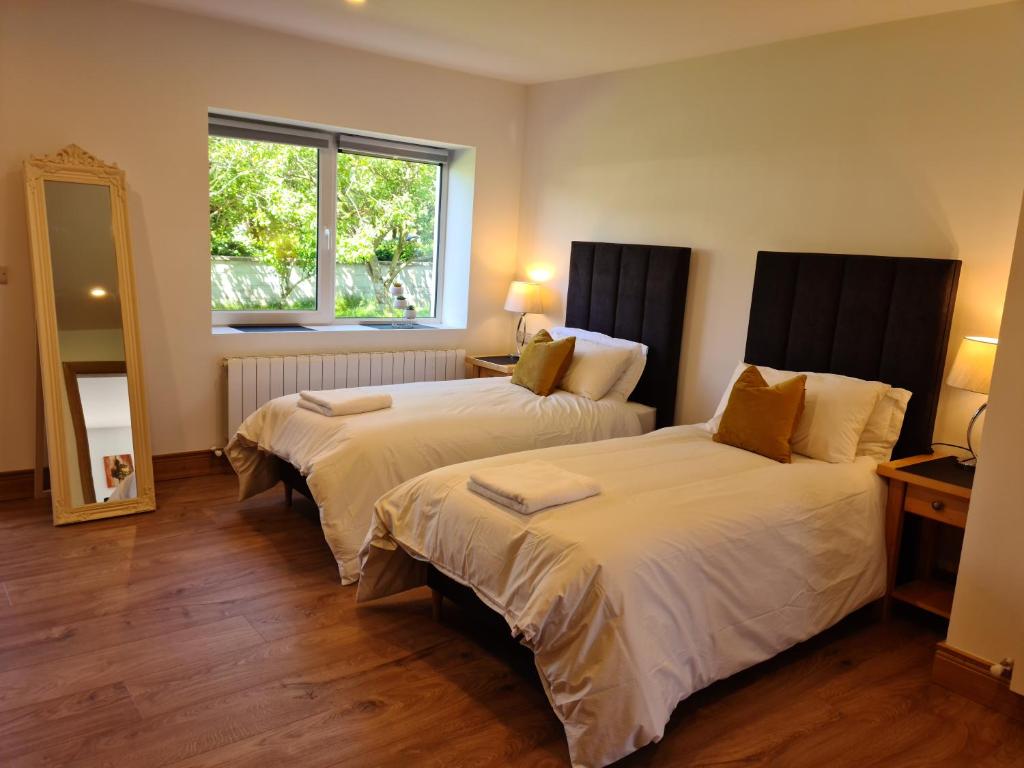 two beds in a hotel room with a window at Ard Kielin Apartment Luxury 2 bedroom in Killarney in Killarney