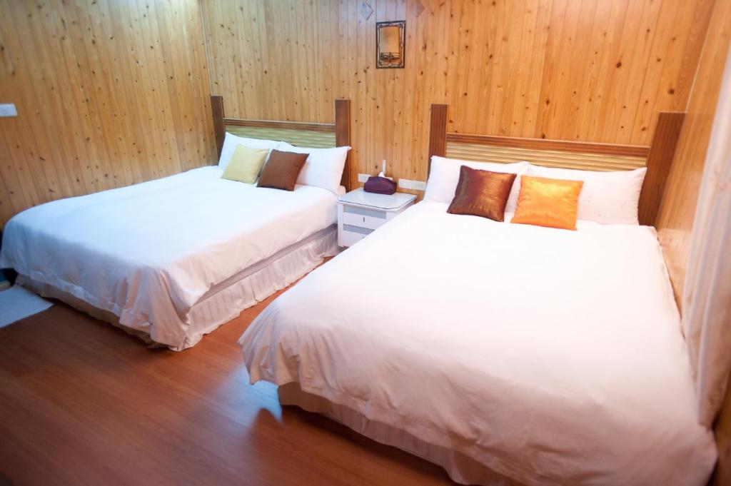 two beds in a room with wooden walls and wood floors at Bay of Stars in Ji&#39;an