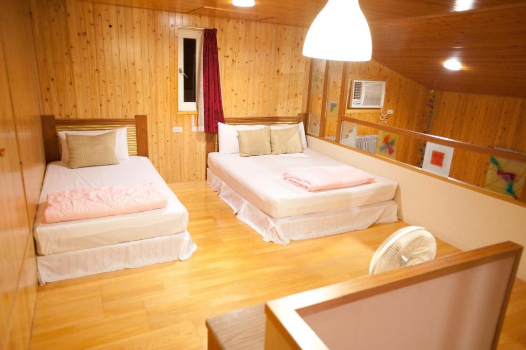 two beds in a room with wooden walls and wood floors at Bay of Stars in Ji&#39;an