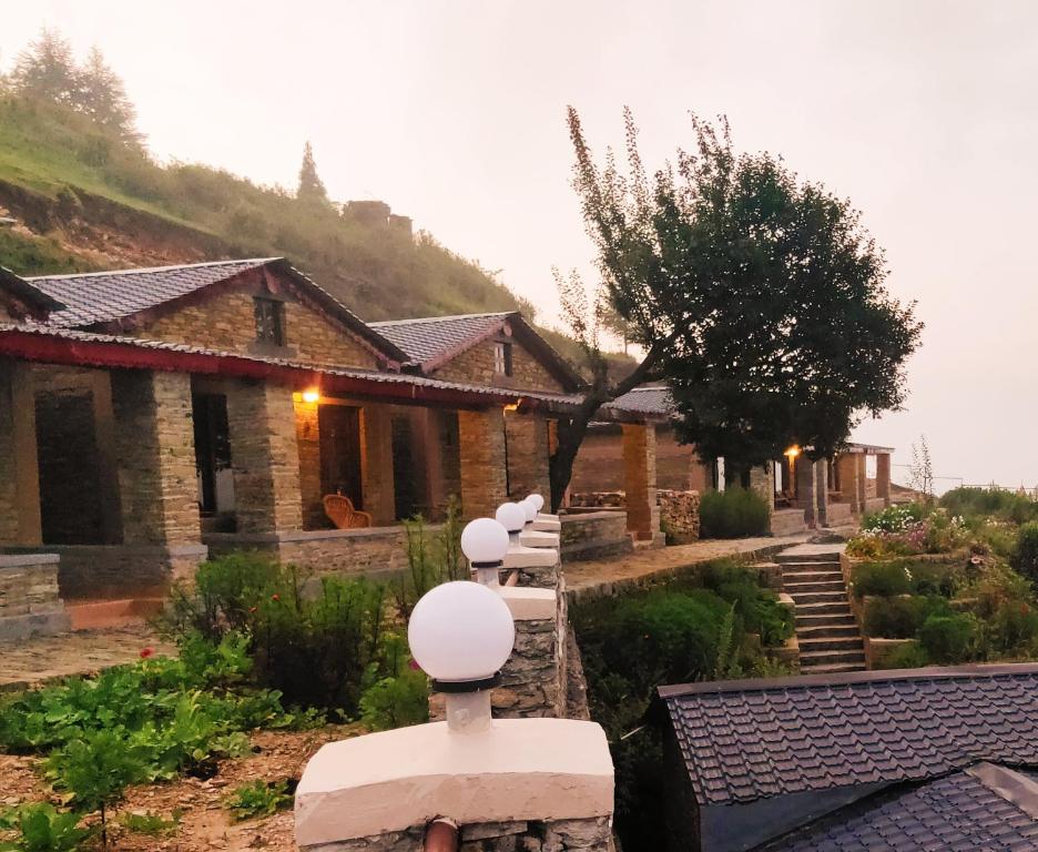 a house with a row of white lights in a yard at Meraki Huts in Pauri