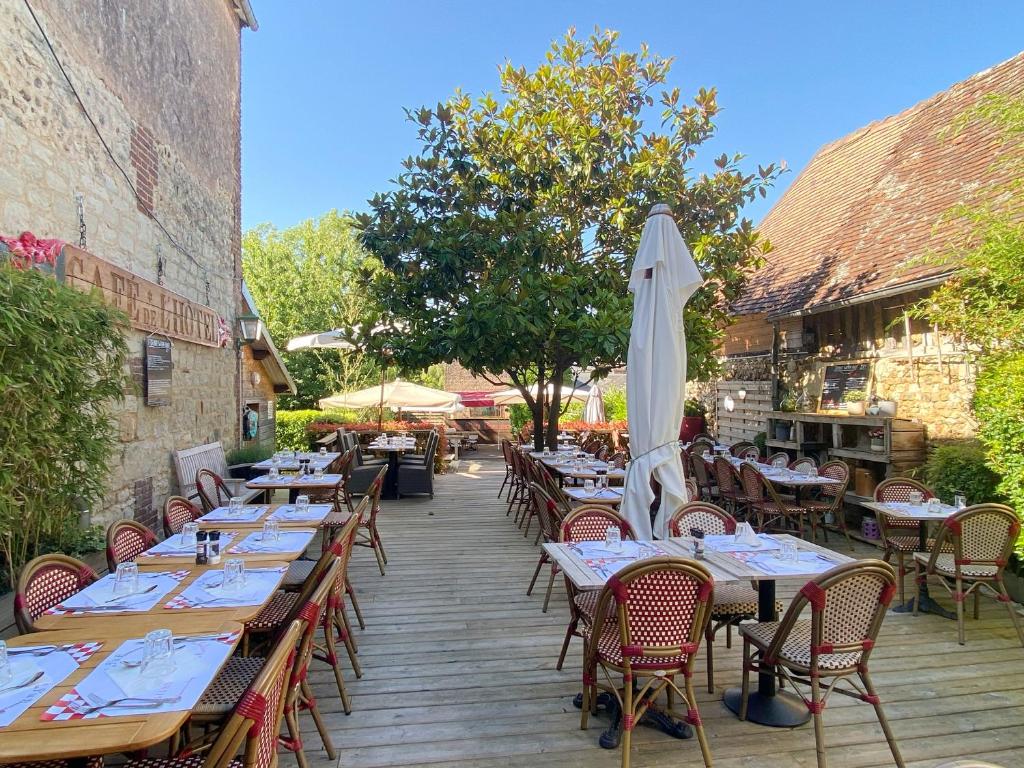 an outdoor restaurant with tables and an umbrella at Hotel le P'tit Beaumont in Beaumont-en-Auge