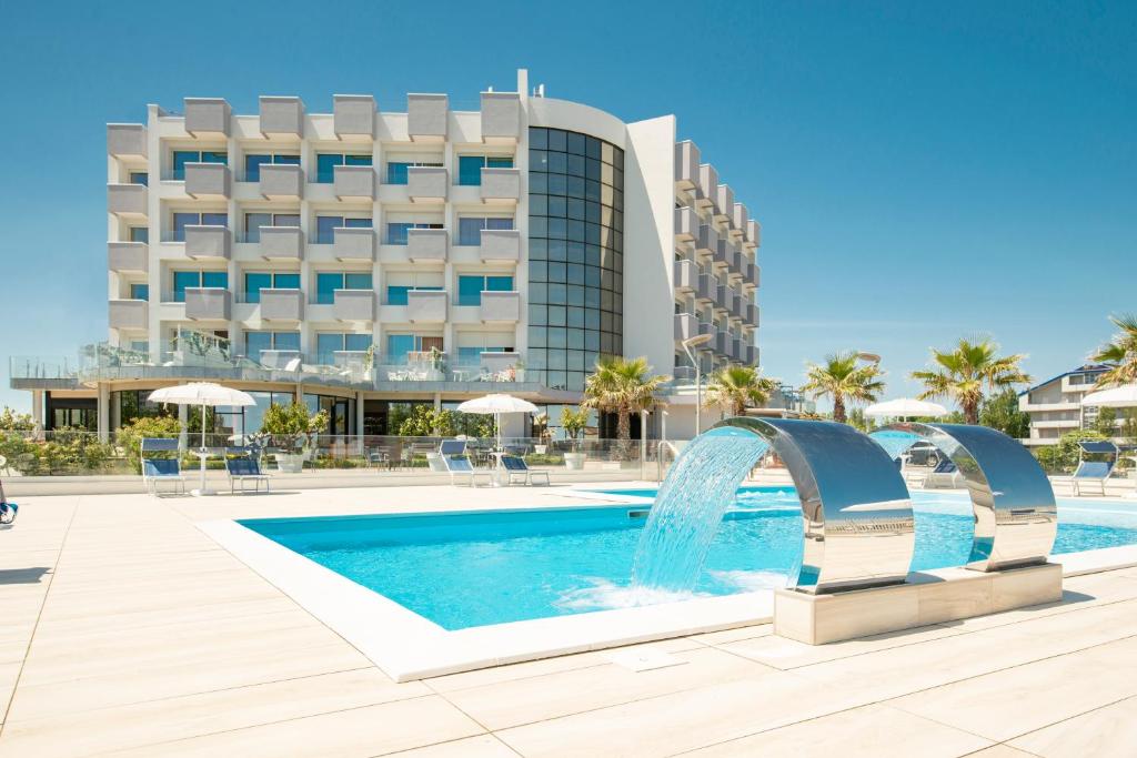 a swimming pool with a fountain in front of a hotel at Hotel Residence Imperial in Misano Adriatico