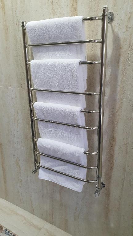 - Baño con toallero eléctrico y toallas blancas en KERUEN SARAY APARTMENTS 6/2 en Türkistan