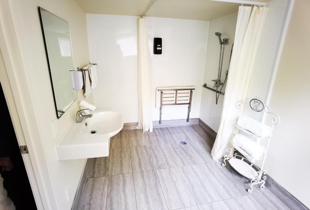 a white bathroom with a sink and a mirror at Kea by the Lake in Te Anau