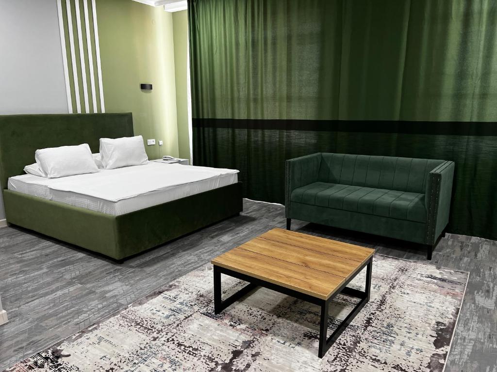 a bedroom with a bed and a couch and a table at KRich Hotel Aktobe in Aktobe
