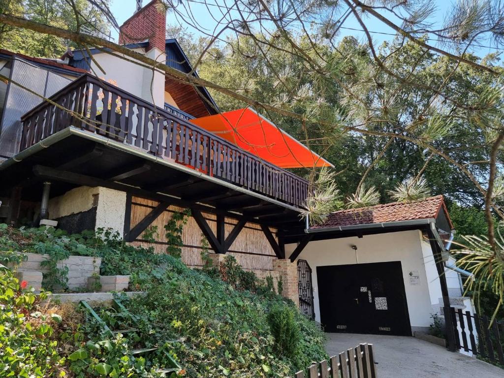 a house with a balcony with an orange umbrella at P10 Nyaraló in Magyarhertelend