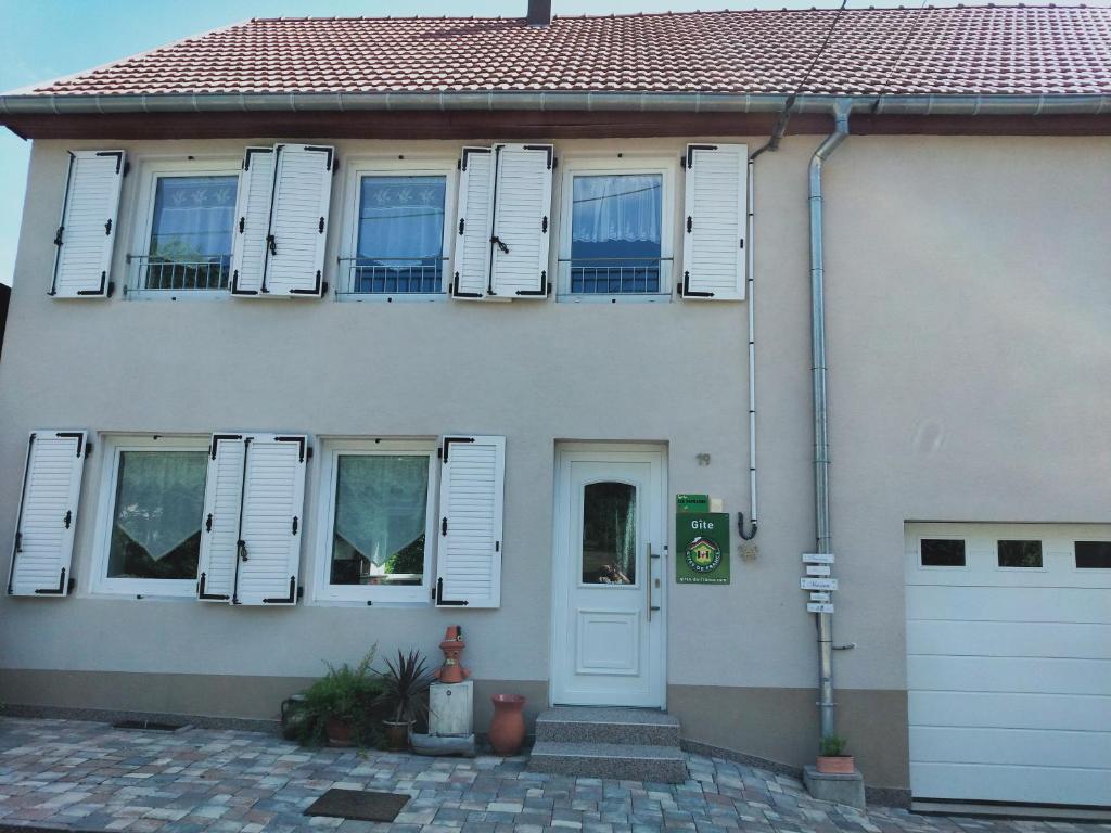 a white house with white shuttered windows and a door at Gîte LES PAPILLONS in Bining-lès-Rohrbach