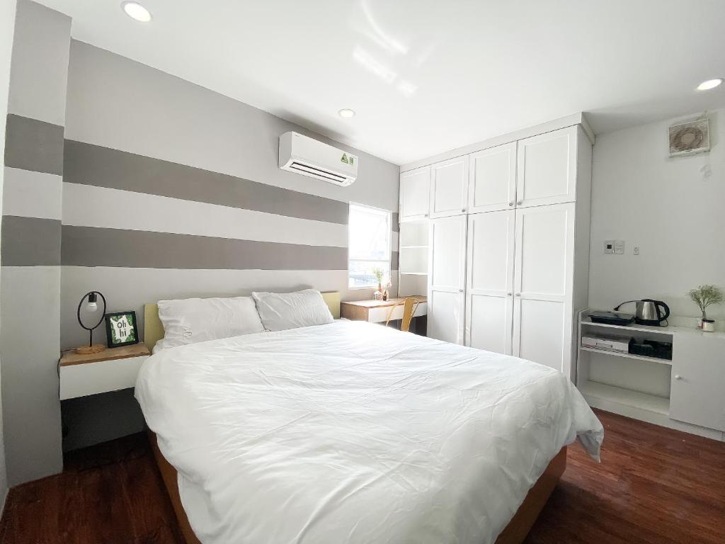 a bedroom with a white bed with a striped wall at B-HOMEAWAY in Ho Chi Minh City