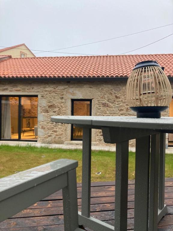 uma gaiola de pássaros sentada numa mesa em frente a uma casa em Casa María da Retratista em Muxía