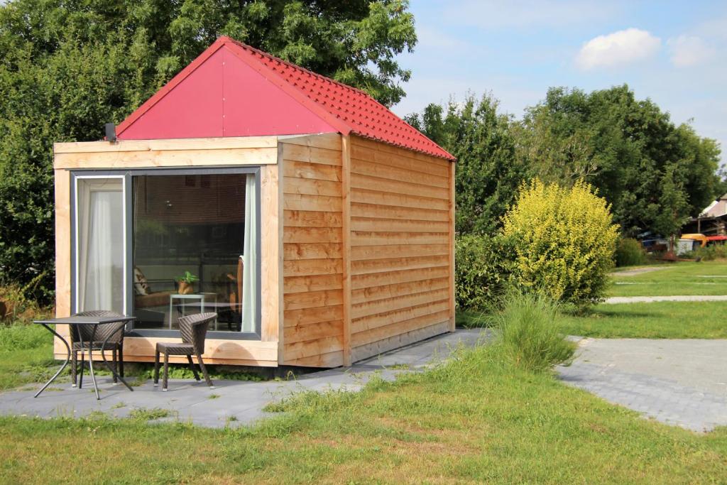 une petite cabane en bois avec un toit rouge dans l'établissement Tiny Cottage 2, à Drijber