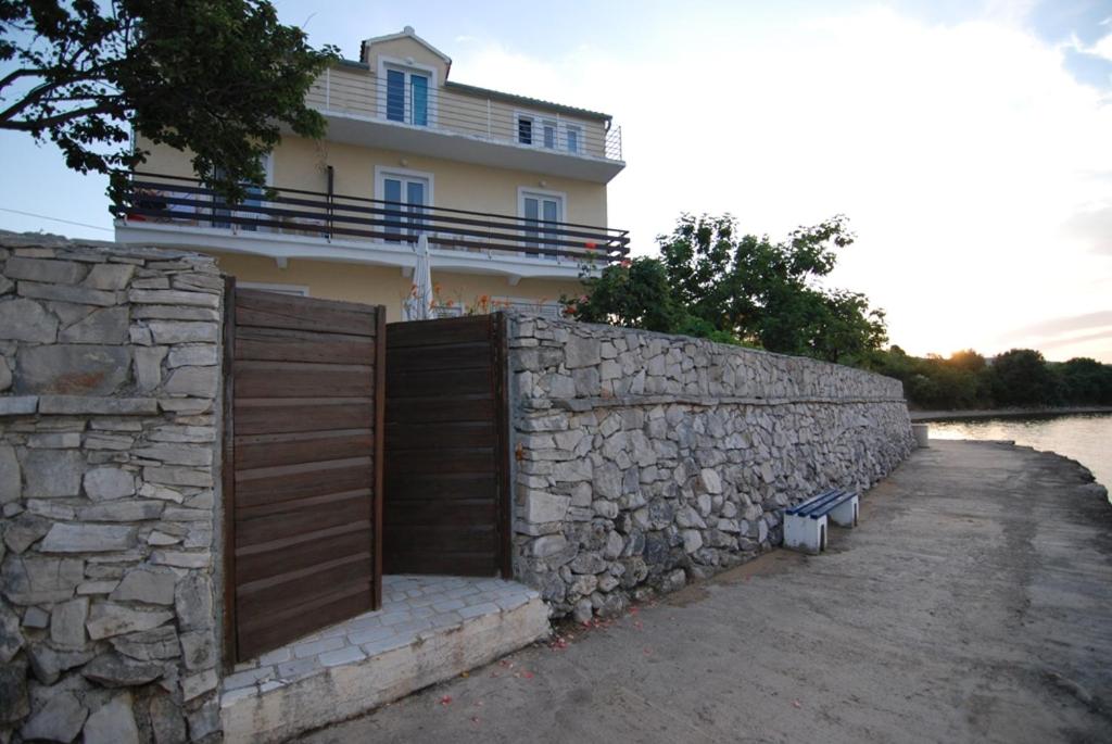 a building with a fence and a stone wall at Apartments Kraj, Tratica Beach in Kraj