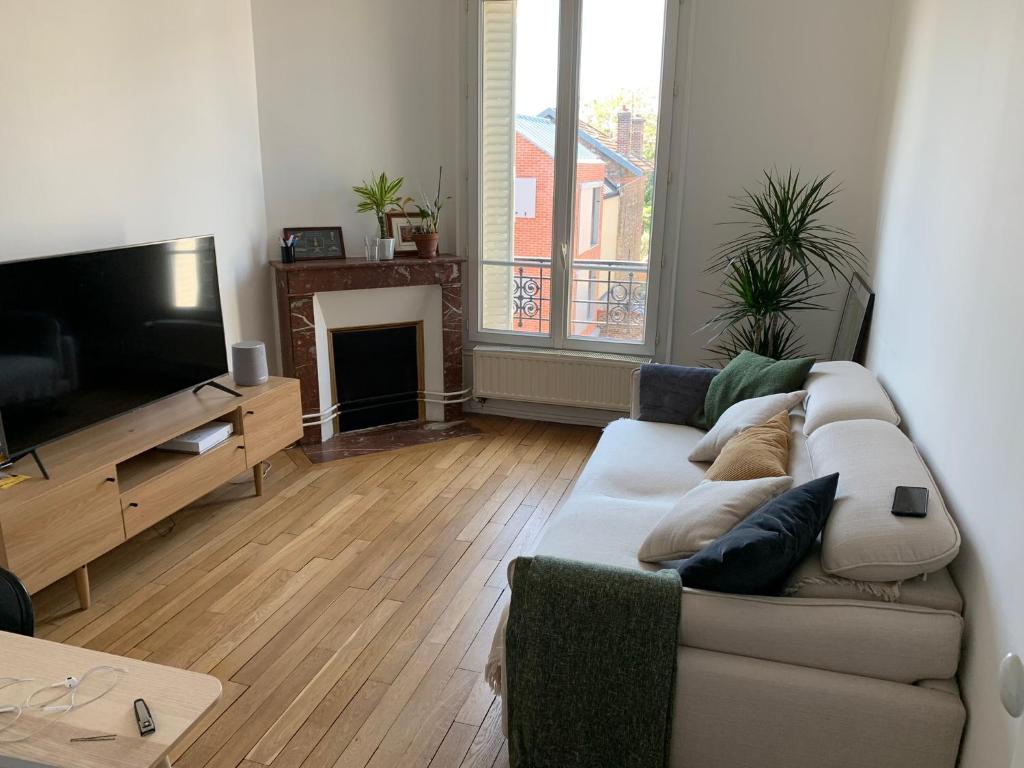 a living room with a couch and a flat screen tv at Appartement tout confort à 10 min de La Défense in Colombes
