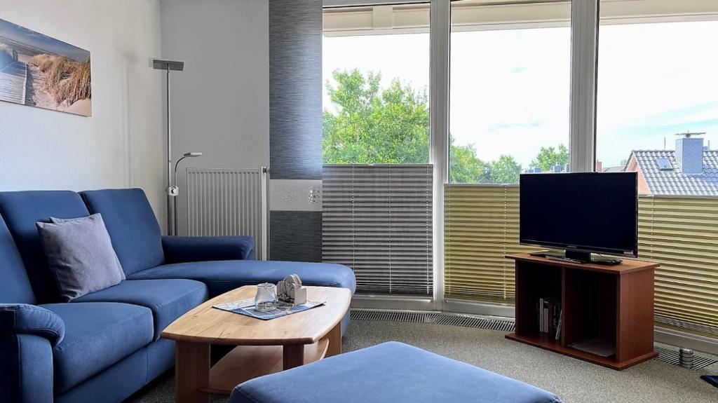 uma sala de estar com um sofá azul e uma televisão em Haus Trafalgar Whg. 242 Möwennest em Cuxhaven