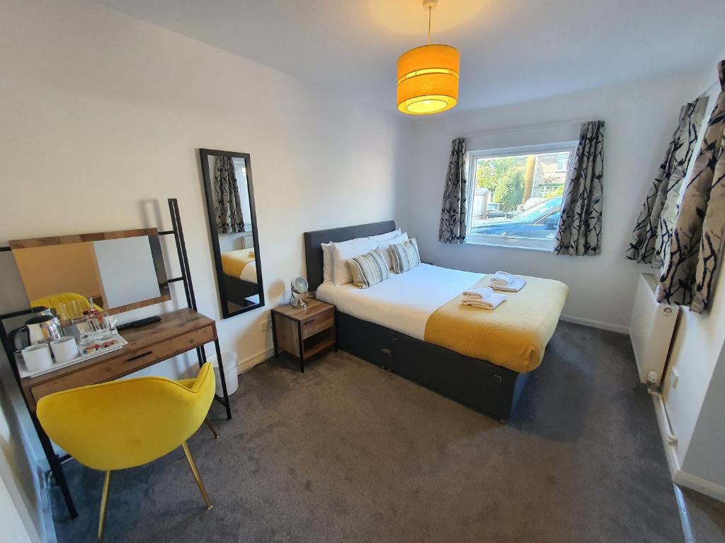 a bedroom with a bed and a desk and a mirror at North Cambridge Guesthouse by Payman Club in Cambridge