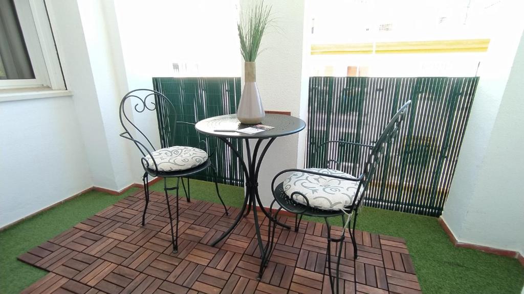 ヘレス・デ・ラ・フロンテーラにあるSherryflat Mérito - Parkingの椅子2脚とテーブル(花瓶付)が備わる客室です。