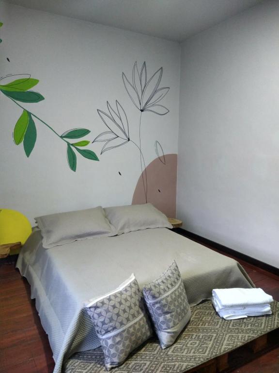 1 dormitorio con 1 cama con hojas pintadas en la pared en Casa la 15 Pereira, en Pereira
