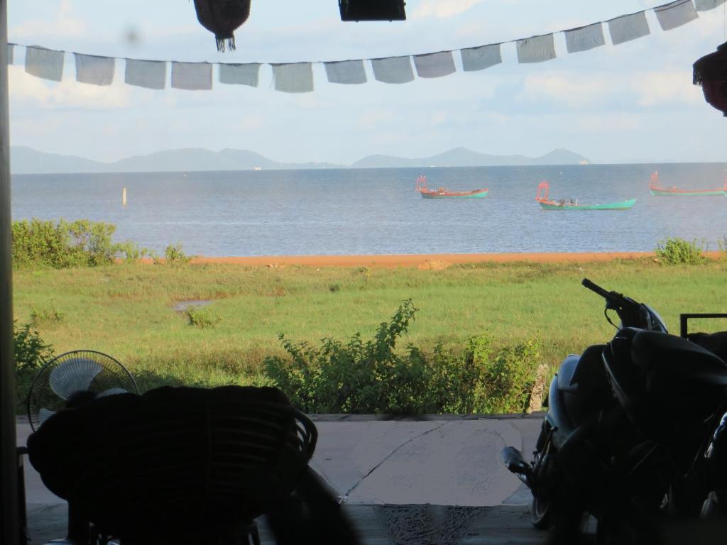 una ventana con vistas al océano y barcos en el agua en Kep Guesthouse, en Kep