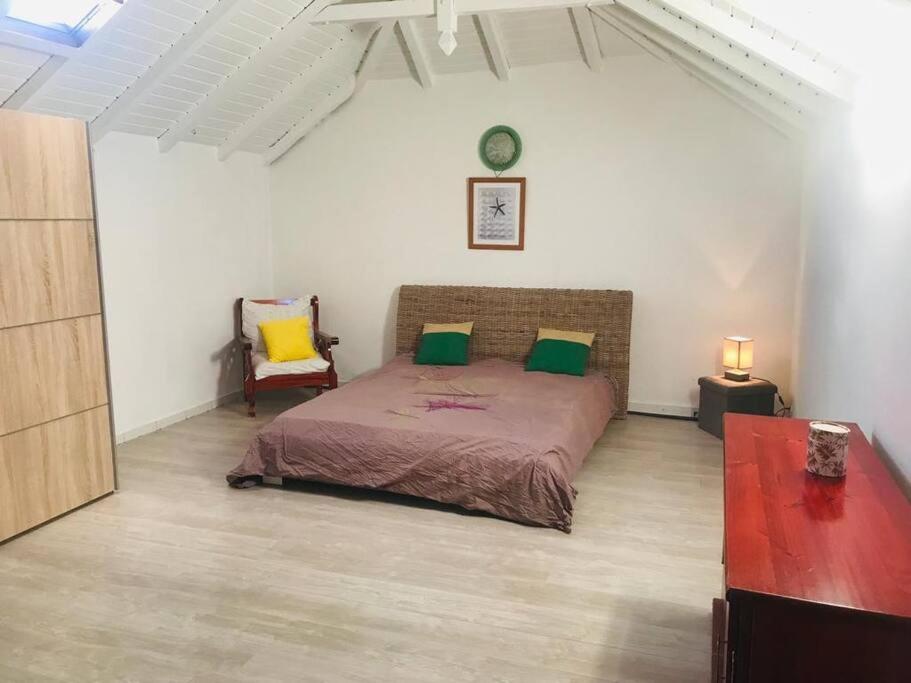 a bedroom with a bed with green and yellow pillows at Villa Sous le Manguier-Anse Bertrand 5min plage in Anse-Bertrand