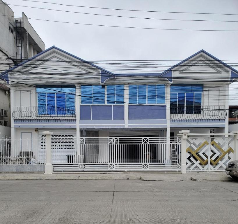 una casa con ventanas azules en una calle en Mimos Le café, en Machala