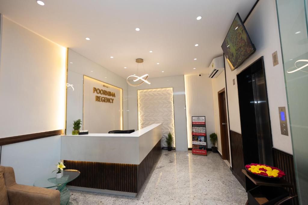 a lobby with a reception desk and a mirror at Poornima Regency in Bangalore