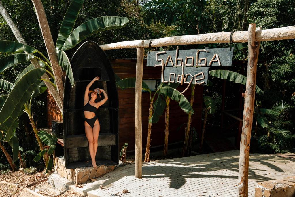 a woman in a bathing suit standing on a sign at Saboga Lodge in Saboga