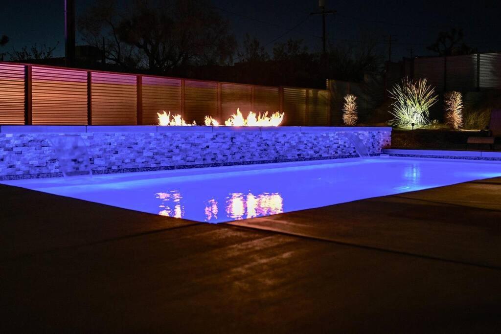 una piscina iluminada por la noche con luces en THREE TREE VILLA w/ EV Charging, en Yucca Valley