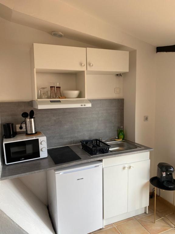 a kitchen with white cabinets and a microwave at Rooftop vue cité médiévale ! in Carcassonne