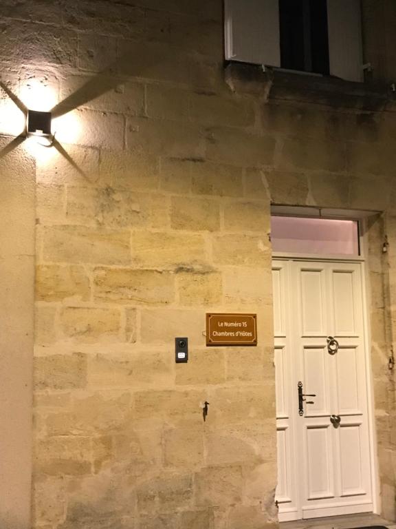 eine Steinmauer mit einer weißen Tür und einem Schild in der Unterkunft Le Numéro 15 in Saint-Seurin-sur-lʼIsle