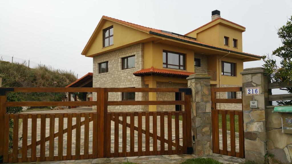 una casa con una puerta de madera y una valla en La Ola de Cantabria en Miengo