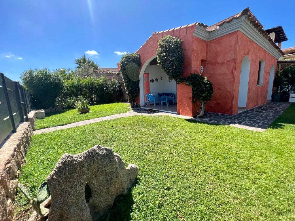 una casa rossa e bianca con un prato di Villa Antonella a San Teodoro