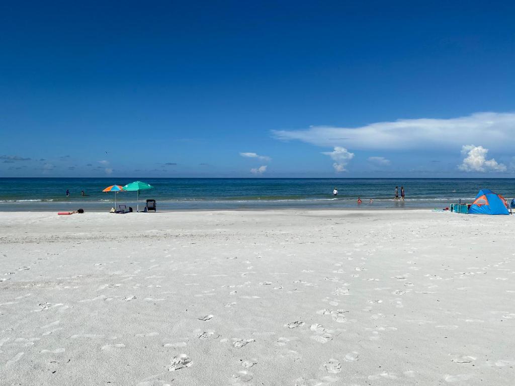 ein Strand mit Sonnenschirmen und Menschen auf dem Wasser in der Unterkunft Belleview Gulf Condos in Clearwater Beach