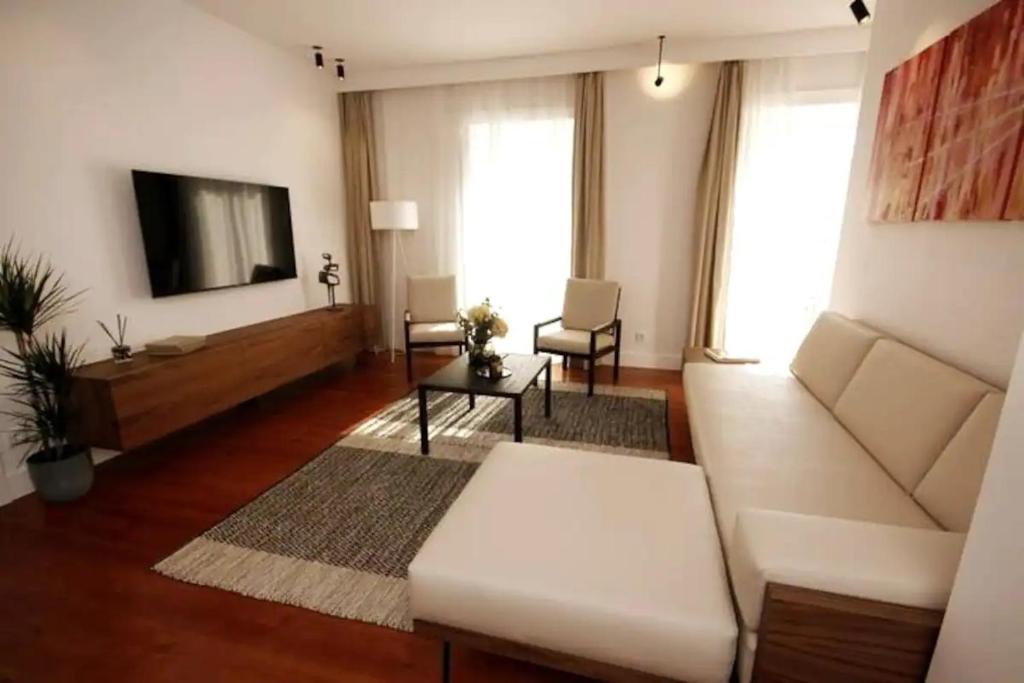Il comprend un salon doté d'un canapé blanc et d'une télévision à écran plat. dans l'établissement Timeless Ambassador -Belém, à Lisbonne